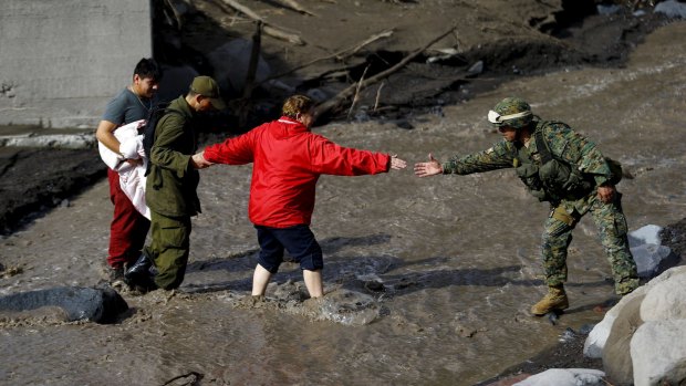 Soldiers help a resident to cross a river after volcanic mudflow from Calbuco at Correntoso, Chile, at the weekend.