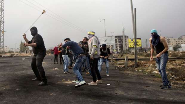 Palestinians protesters throw stones at Israeli troops during clashes in the West Bank city of Ramallah on Monday. 