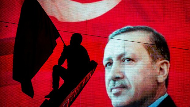 A supporter of Turkish President Recep Tayyip Erdogan waves a flag against an electronic billboard during a rally in Kizilay Square in July.