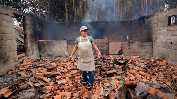 Inocencia Rodrigues, 64, walks among the debris of the burnt shed where she raised chickens and pigs in the village of Sao Joaninho, northern Portugal.
