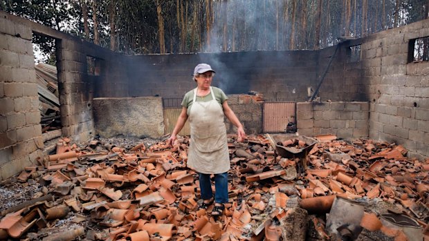 Inocencia Rodrigues, 64, walks among the debris of the burnt shed where she raised chickens and pigs in the village of Sao Joaninho, northern Portugal.