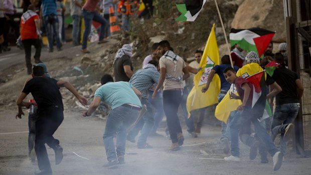 Palestinians run from tear gas during clashes with Israeli security forces at the Hizme checkpoint near the West Bank city of Ramallah, on Wednesday,  as Palestinian President Mahmoud Abbas addressed the UN General Assembly.