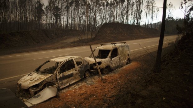 Burnt cars on the side of the road after a wildfire took dozens of lives on June 18.