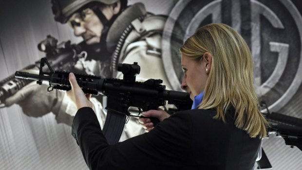 A woman tries out a SIGM400 rifle during the Defence & Security Equipment International arms fair in London in 2013.