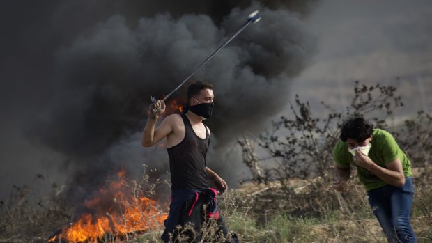 A Palestinian protester uses a sling shot to hurl stones during clashes with Israeli soldiers by the Israeli border with Gaza on Friday. 