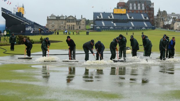 Staff clear the course of water after heavy rainfall delayed the start to the second round.