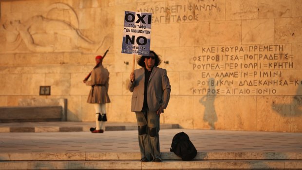 A lone protester stands on the steps in front of the Greek parliament as demonstrators march through Athens during an anti-austerity rally on Friday.