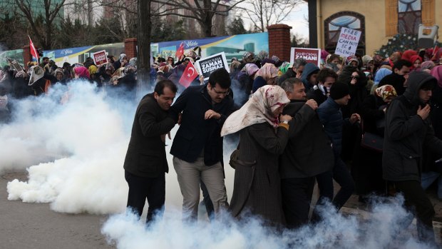 People run as riot police use tear gas and water cannons to disperse a crowd who are showing their support for the Zaman newspaper in Istanbul.