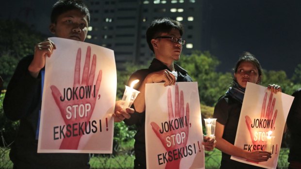 Activists hold posters which read "Jokowi, stop the executions!" during a candle light vigil outside the presidential palace in Jakarta, on Thursday.