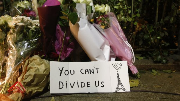 Flowers stand next to a sign near the Bataclan concert hall.