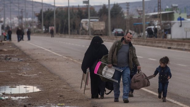 People fleeing air strikes walk to a temporary refugee complex on Sunday.