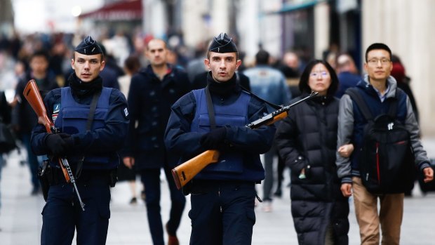 Pedestrians walk alongside police officers  in the Champs Elysees in Paris, the day after the November 13 terrorist attacks. 