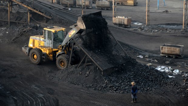 A worker watches a bulldozer unload coal at a mine in central China's Anhui province last month.