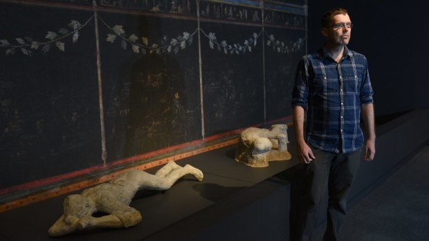 Curator Will Mather with some plaster casts of people killed in the eruption of Mount Vesuvius in 79AD.