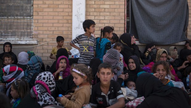 Women and children from Hawija sit outside a Kurdish screening centre in Dibis, Iraq. 
