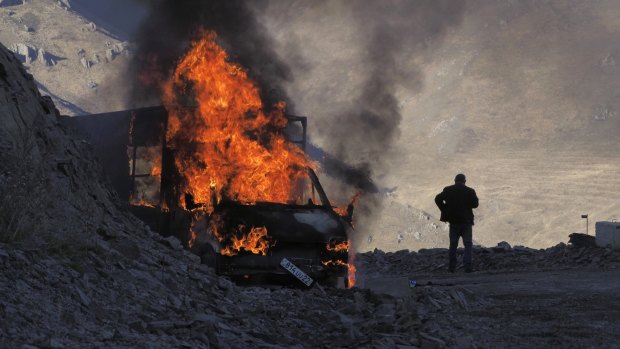 A man stands near his burning car which caught on fire during the climb along the road to a mountain pass, near the border between Nagorno-Karabakh and Armenia.