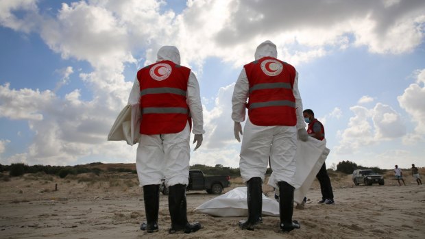Red Crescent workers look at the corpse of a migrant on a beach near the port of Khoms, Libya, on October 25.