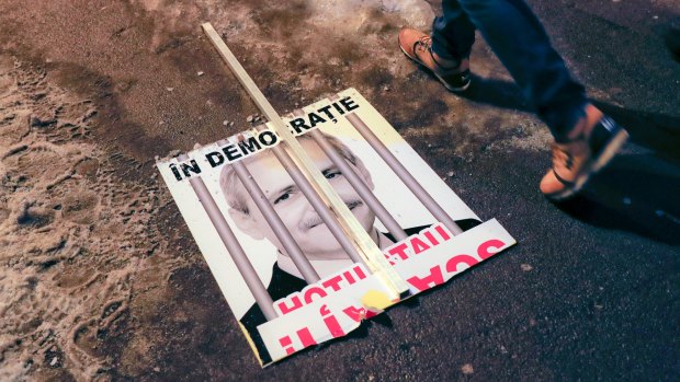A broken poster depicting the leader of the ruling Social Democrat party Liviu Dragnea, which reads "In a democracy, thieves are in jail", lies on the pavement in Bucharest, Romania.