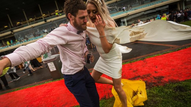 Francis Kavanagh helps his girlfriend Tiarne Coxhill across a muddy area at Cox Plate day at Moonee Valley racecourse.