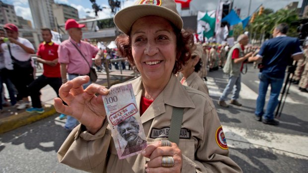A member of the ruling party's militia shows a sample of a banknote with the image of opposition leader Henry Ramos Allup and a stamp that reads "out of circulation" in Spanish at the rally.
