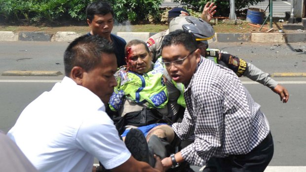 People carry an injured police officer near the site where an explosion went off at a police post during the Jakarta attacks in January.