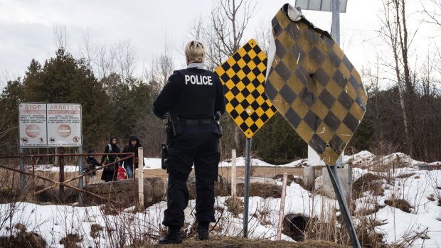 A Royal Canadian Mounted Police officer warns a family they will be arrested if they cross into Canada from Champlain, New York state, on February 23.