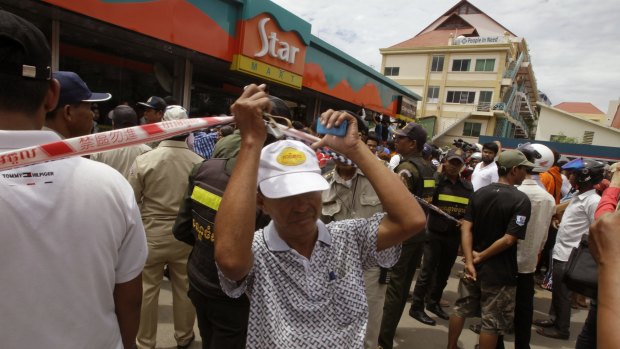 People stand outside a petrol station convenience store where Kem Ley, a political analyst was killed.