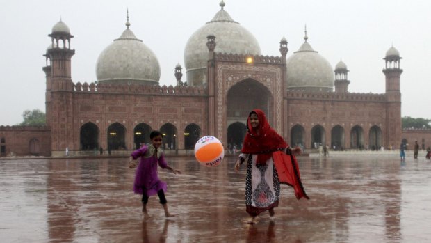 Pakistani children play in the rain outside the historic Badshahi Mosque in Lahore, Pakistan, on Friday.