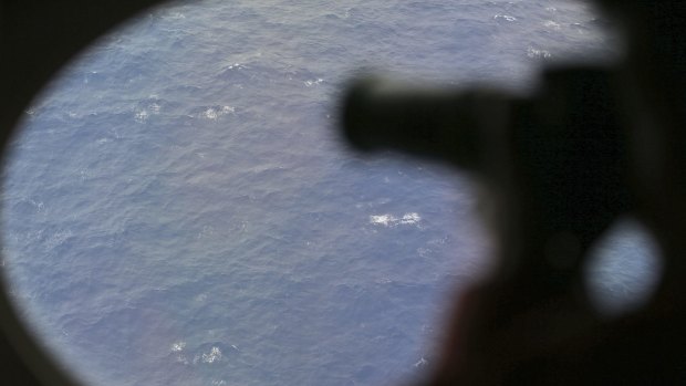 An observer on a Japan Coast Guard Gulfstream aircraft takes photos out of a window while searching for MH370.