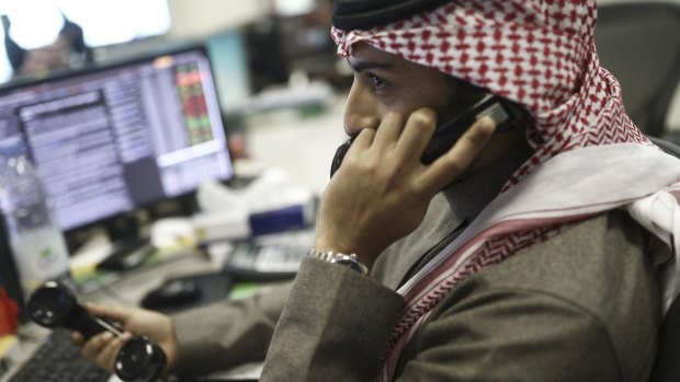 An employee speaks on the phone at the Alawwal Bank as financial data is displayed on computer screens on the bank's trading floor in Riyadh, Saudi Arabia where the central bank is said to have been crippled by malware.