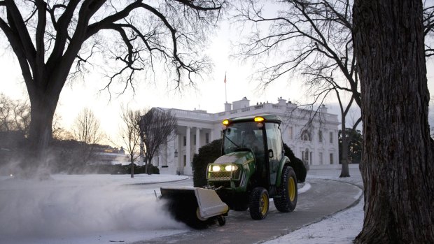 The calm before the snowstorm ... A worker with the National Park Service sweeps snow from a walkway at the White House in Washington on Thursday.