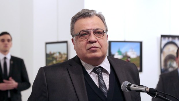 Andrei Karlov pauses during his speech, moments before Mevlut Mert Altintas, seen in the background, shoots him.