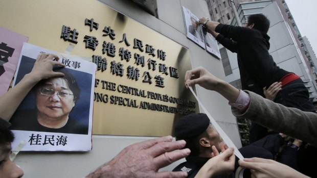 Protesters with photos of missing booksellers during a protest outside the Liaison of the Central People's Government in Hong Kong. 