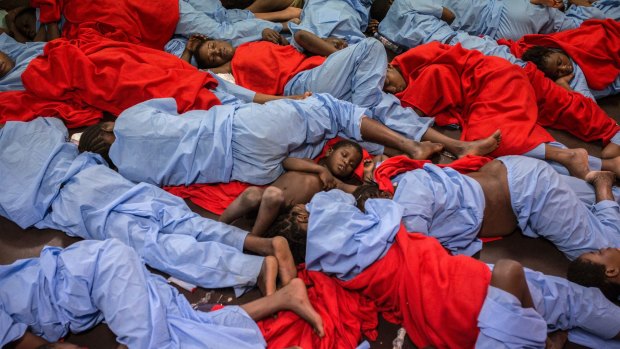Idris 3, from Mali, centre, sleeps next to his mother Aicha Keita, right, on the deck of the Golfo Azzurro vessel after being rescued from the Mediterranean sea off Libya in January.