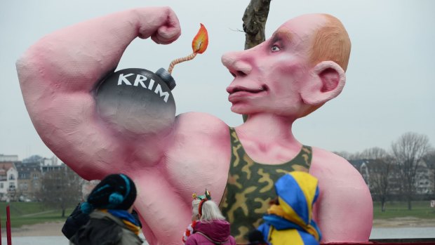 People look at a figure of Russian President Vladimir Putin showing a bomb reading "Crimean" on his arm during the traditional Rose Monday parade in Duesseldorf, Germany.