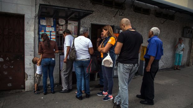 Customers stand in line to purchase animal lottery tickets in Caracas, Venezuela. Some have put their faith in the peculiar game, where a rooster can help you reach the end of the month.