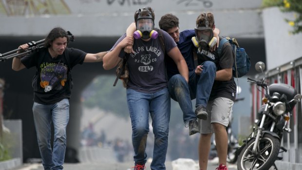 Demonstrators carry a youth away from tear gas fired by police during an opposition demonstration in Caracas last week. 