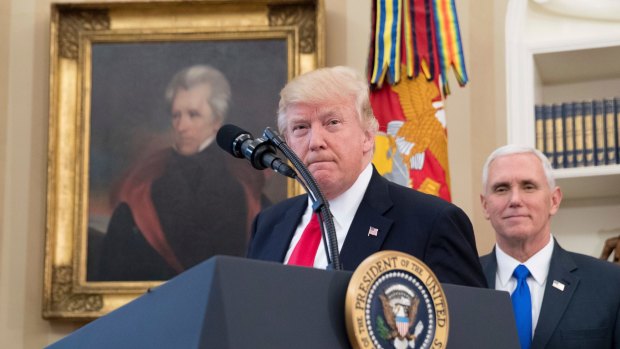 A portrait of former US president Andrew Jackson hangs on the wall behind President Donald Trump, accompanied by Vice President Mike Pence, in the Oval Office.