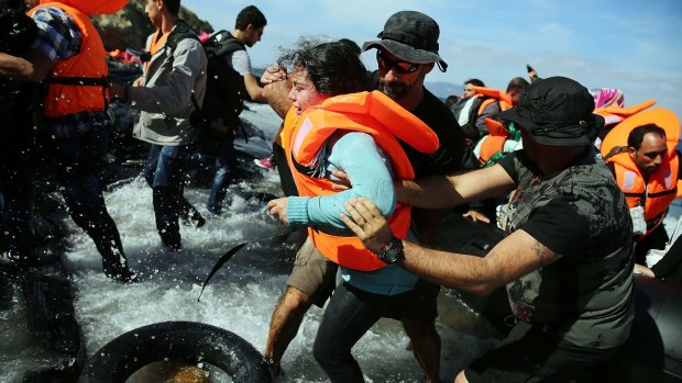 People are assisted moments after they arrive with other Syrian and Iraqi refugees on the island of Lesbos from Turkey on Wednesday.