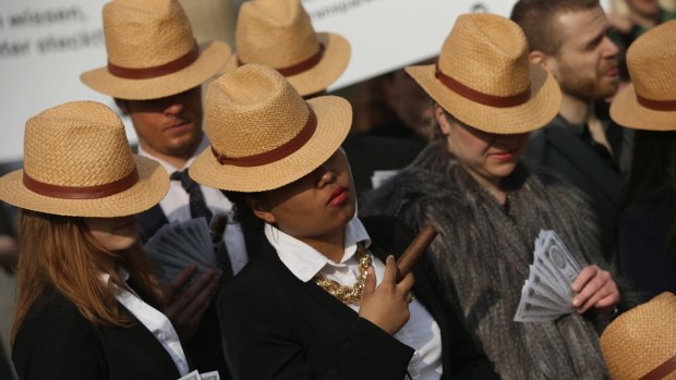 German activists wearing suits and Panama hats hold fake money while demanding greater transparency following the Panama Papers affair.