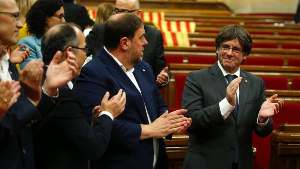 Catalonia regional President Carles Puigdemont, right, applauds with parliamentarians, after the vote to set the referendum date.