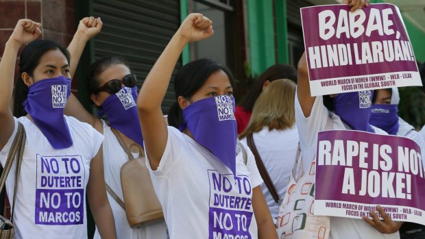 Protesters clench their fists as they block traffic in a protest against the candidacies of front-running presidential candidate Rodrigo Duterte and vice-presidential candidate Ferdinand "Bongbong" Marcos Jr.