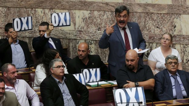 Far-right Golden Dawn party lawmakers hold placards that read 'no' in Greek as party spokesman Christos Pappas speaks during a parliamentary session in Athenson Saturday.