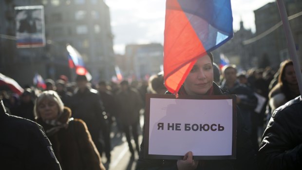 Demonstrators carry Russian flags and a poster reading "I Have No Fear" during the march.