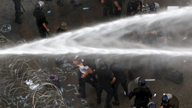 Protesters are sprayed with water as police arrest a man  near the government palace in Beirut.