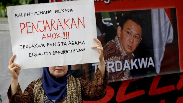 A Muslim woman holds up a poster that reads "Put Ahok, the blasphemer, in jail" during a protest against Jakarta's minority Christian Governor Basuki "Ahok" Tjahaja Purnama  last week.