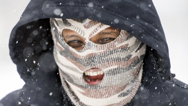 A masked man walks on King Street as snow falls in Alexandria, Virginia on  Saturday.