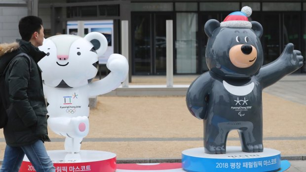 A man passes by official mascots of the 2018 Pyeongchang Winter Games, a white tiger "Soohorang" for the Olympic, and the Asiatic black bear "Bandabi" for the Paralympic, in downtown Seoul.