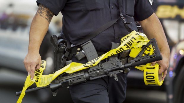 A police officer deploys tape in San Bernardino, California.