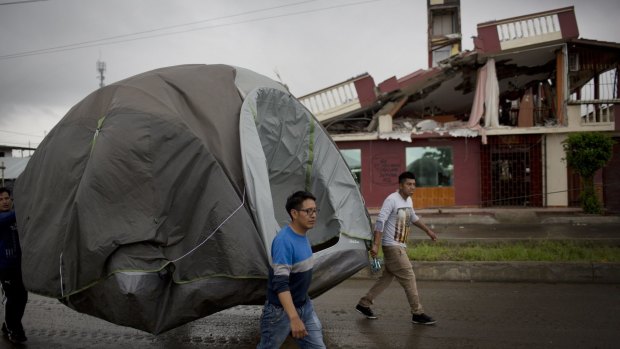 Volunteers move a tent to a new camp for residents affected one week after the devastating earthquake in Pedernales, Ecuador.